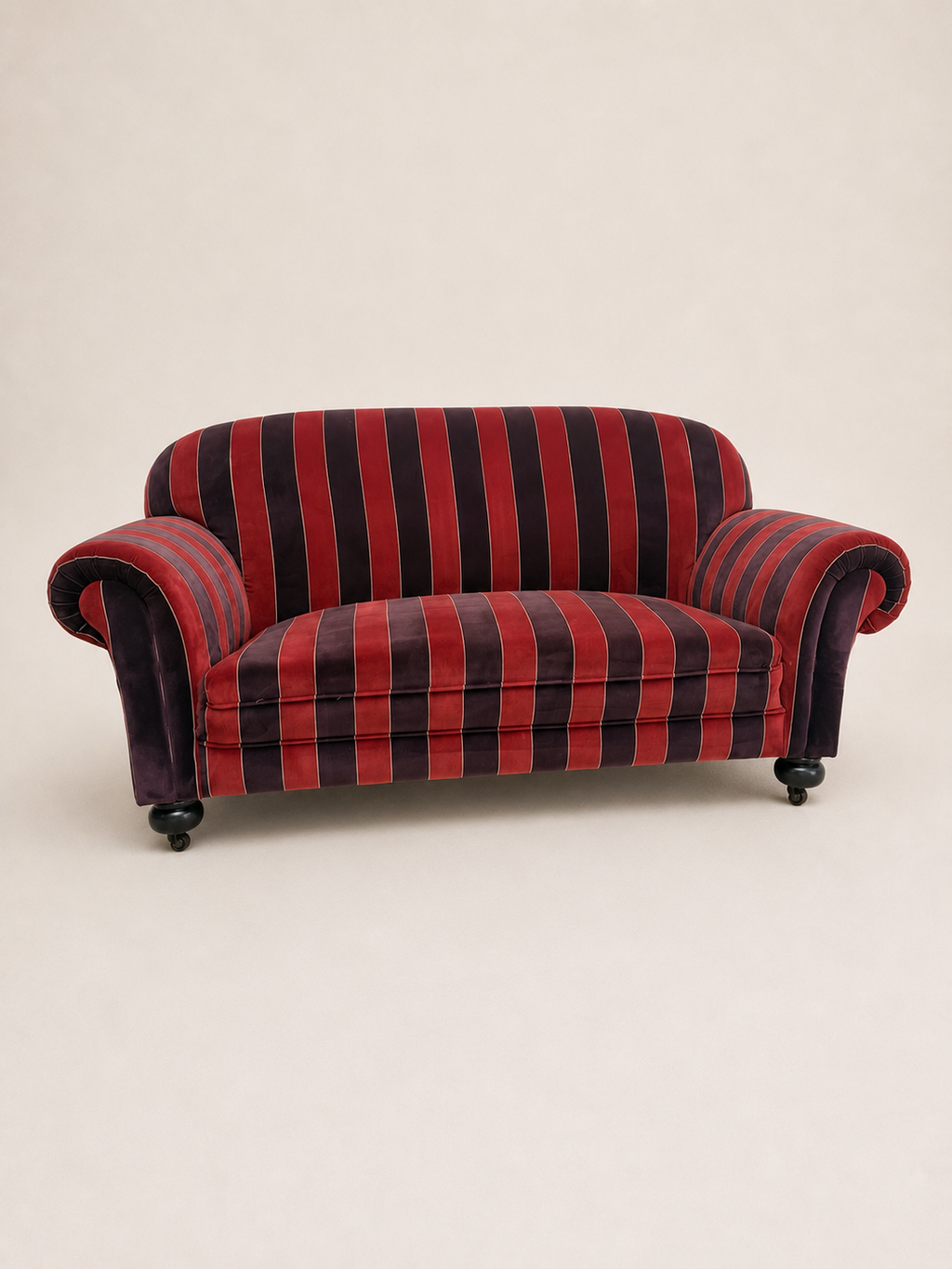 A small upholstered armchair with red and purple vertical stripes, photographed against a plain light beige studio background.