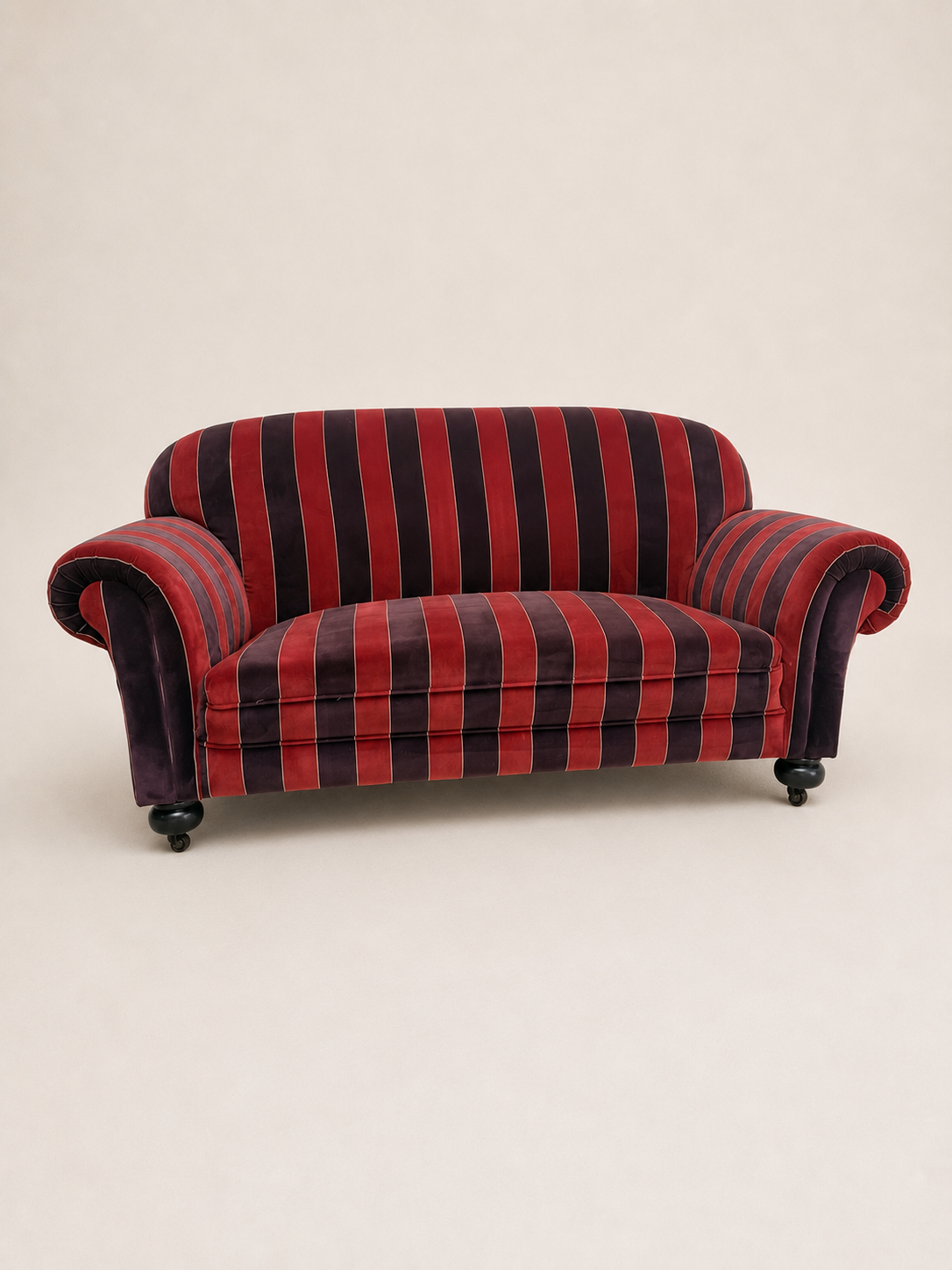 A small upholstered armchair with red and purple vertical stripes, photographed against a plain light beige studio background.