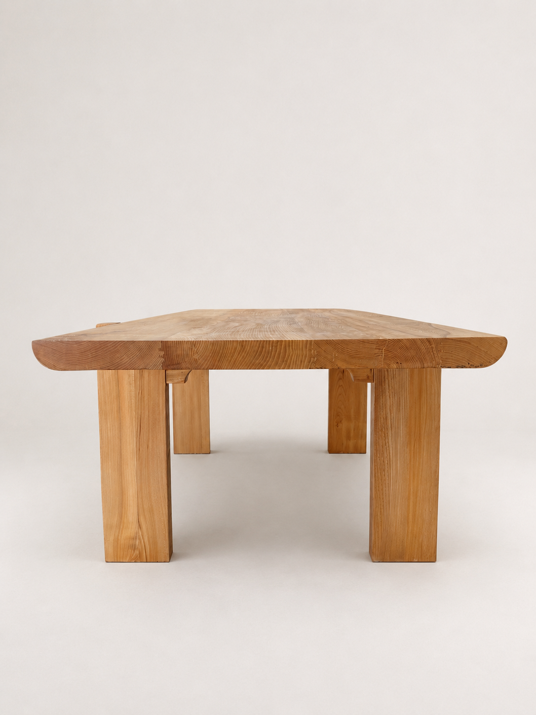 A low, rustic wooden table with a hexagonal top and thick block legs, shown against a plain light gray studio background.