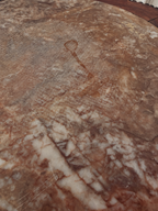 A close-up of a polished stone surface with natural marbled patterns in warm brown, beige, and cream tones.