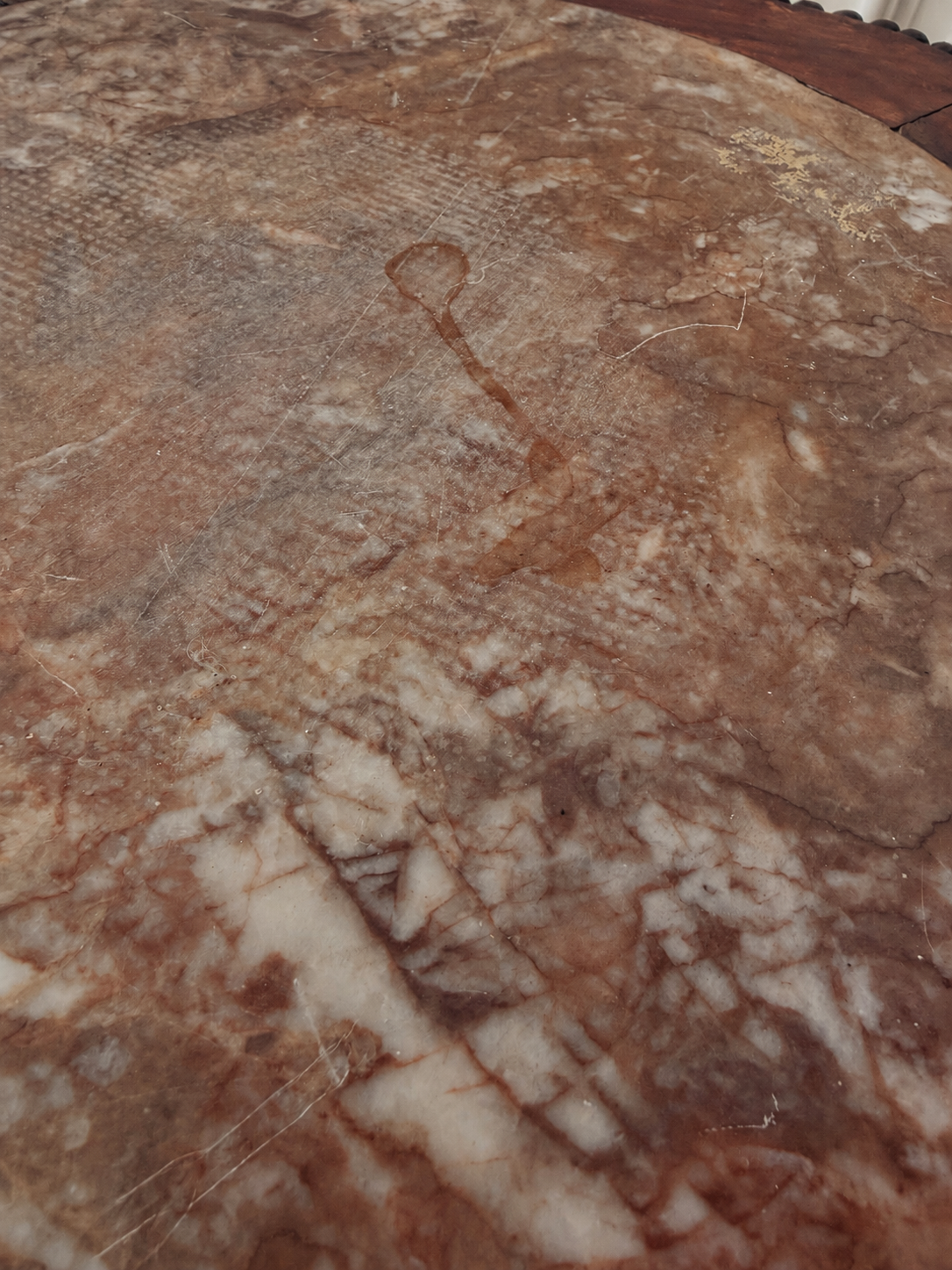 A close-up of a polished stone surface with natural marbled patterns in warm brown, beige, and cream tones.