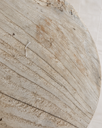 A close-up of a round wooden board or tray with a distressed, weathered finish showing natural wood grain and texture.