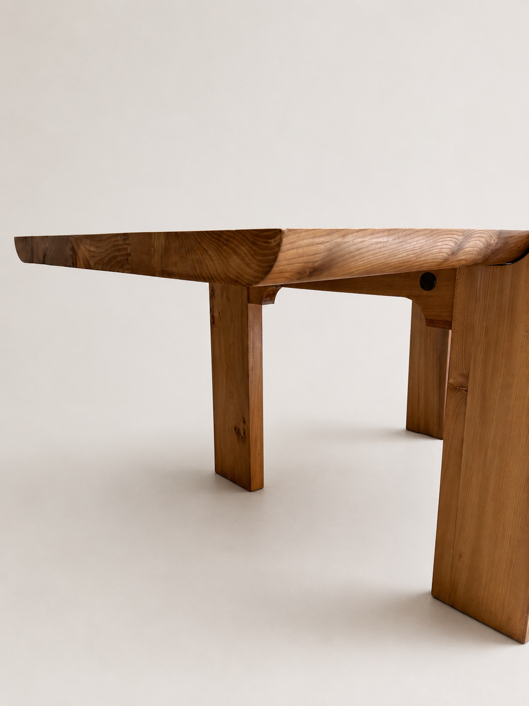 A close-up studio shot of a wooden dining table showing the thick, live-edge tabletop and sturdy block-style legs against a plain light background.