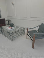 Italian chrome and glass stacked coffee table - three-quarter room view beside an armchair