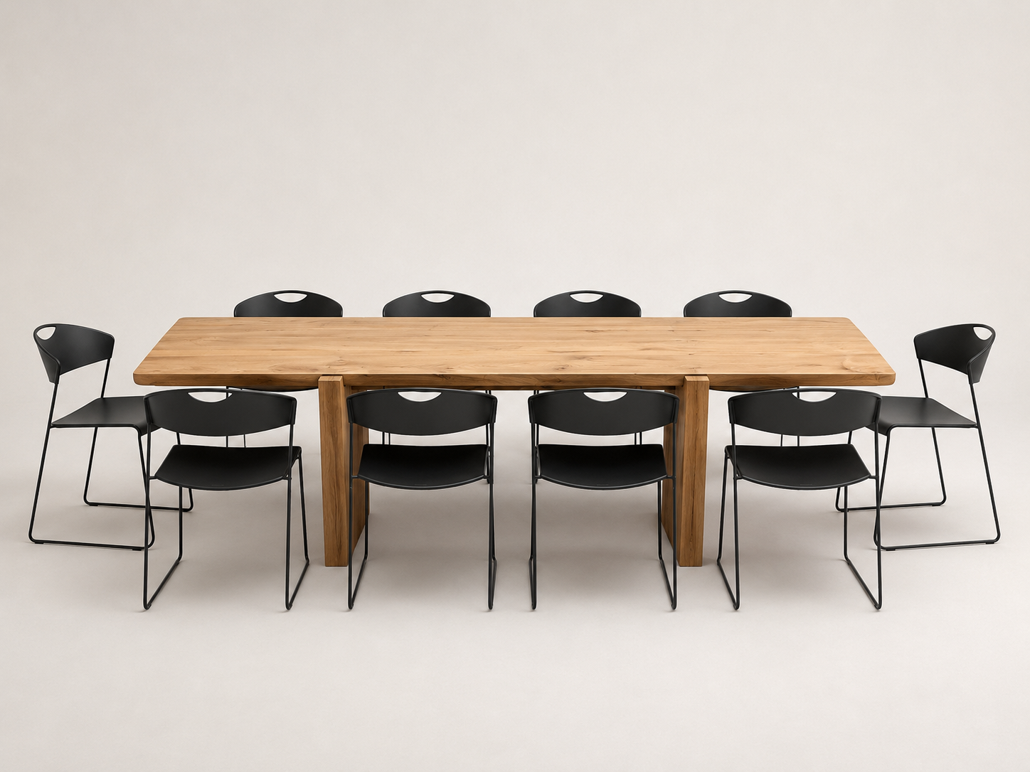 A rectangular wooden conference table with eight black metal-framed chairs, photographed against a seamless light gray studio background.