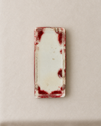 A rectangular ceramic vase with rounded corners, featuring a glossy off-white center and a textured, dark red glazed border with organic mottled patterns.