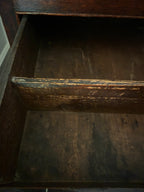 Close-up of the inside of a dark brown wooden drawer with a distressed finish showing worn wood grain and chipped paint.