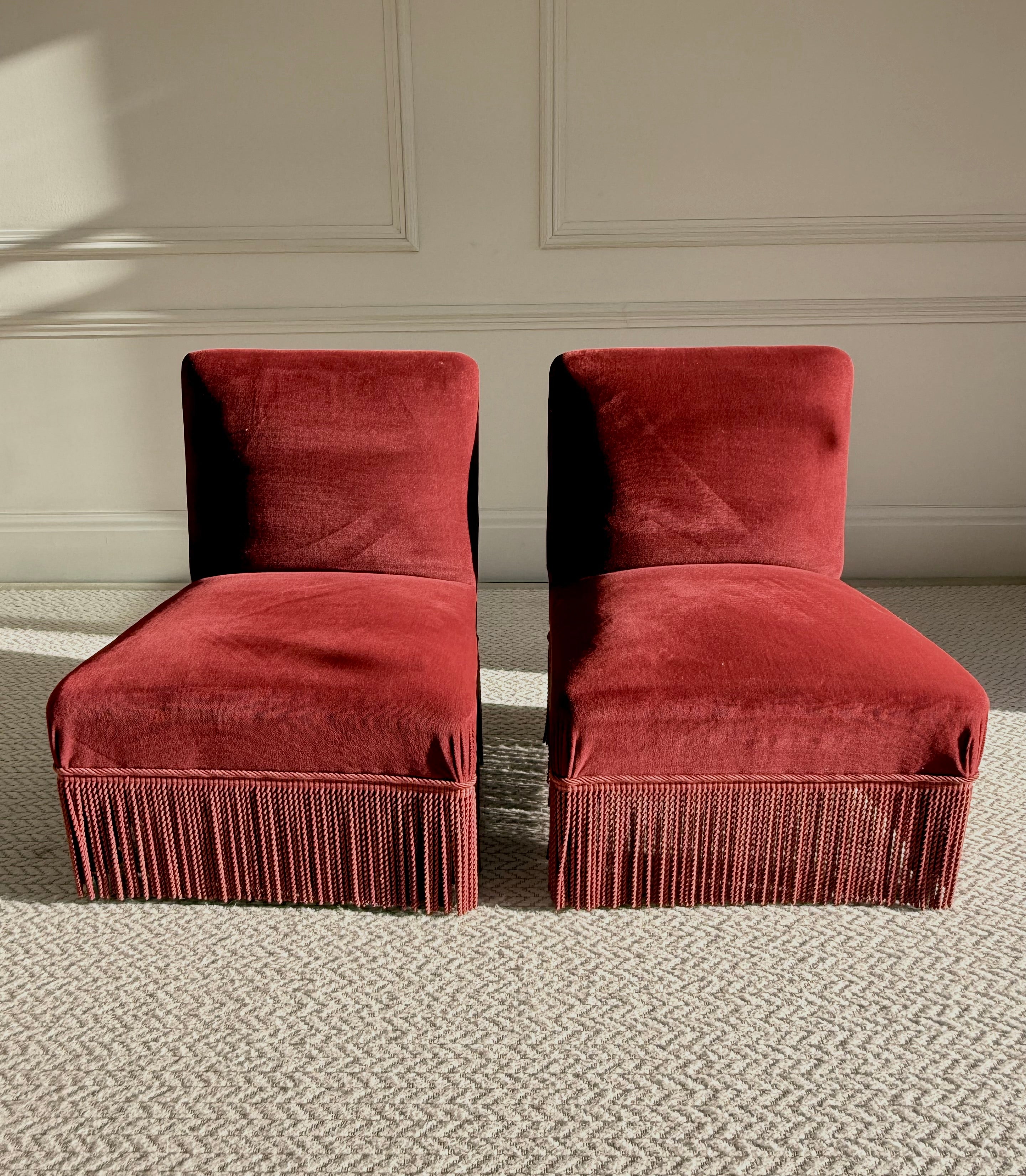 A pair of French Napoleon III red velvet slipper chairs with fringe
